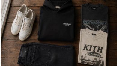 Stack of folded heavyweight streetwear hoodies and graphic tees on a wooden bench in soft daylight